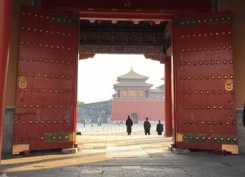 A distant pavilion framed by large red doors