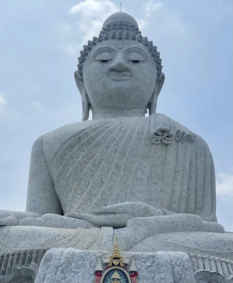 A large seated Buddha statue beneath a cloudy sky