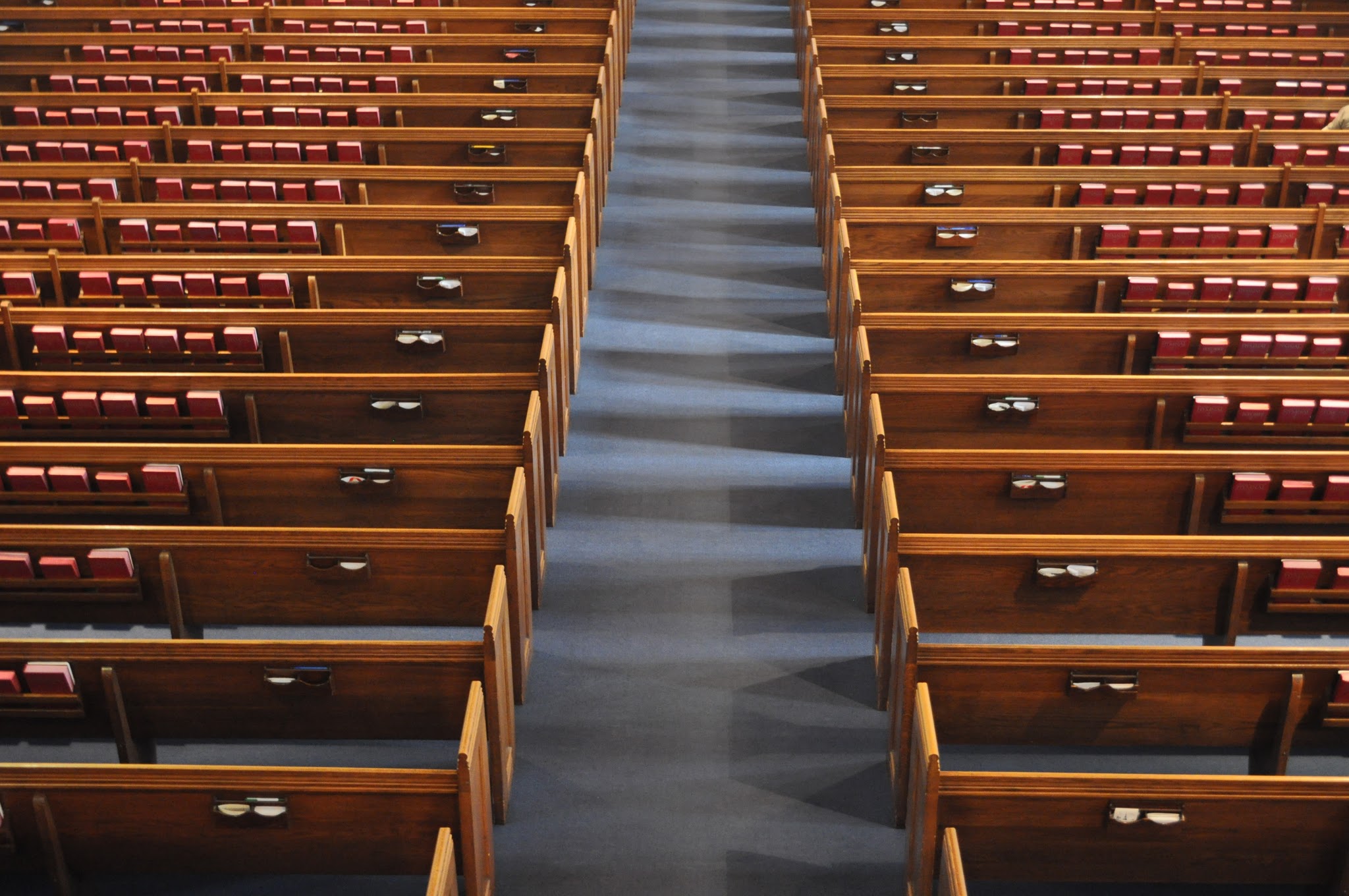 Rows of wooden church pews and red hymnals beside a central aisle