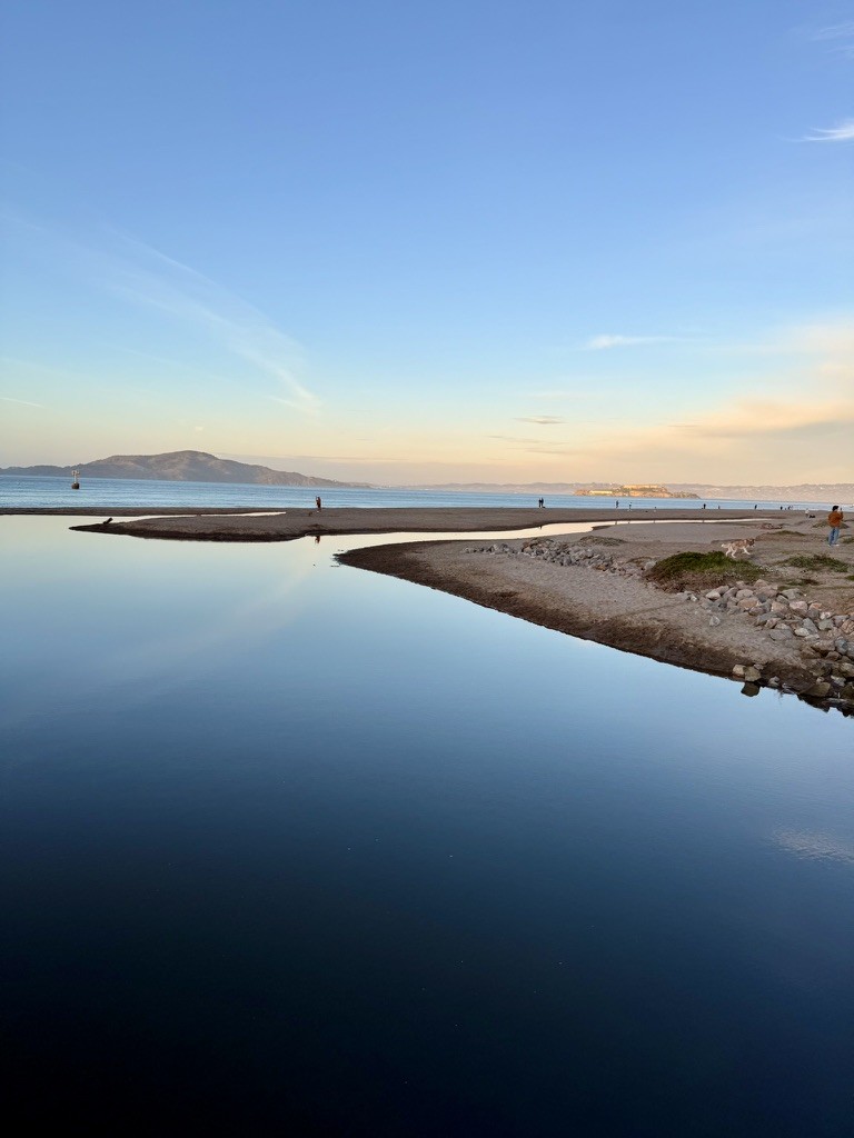 A sandbar reflected in still blue water
