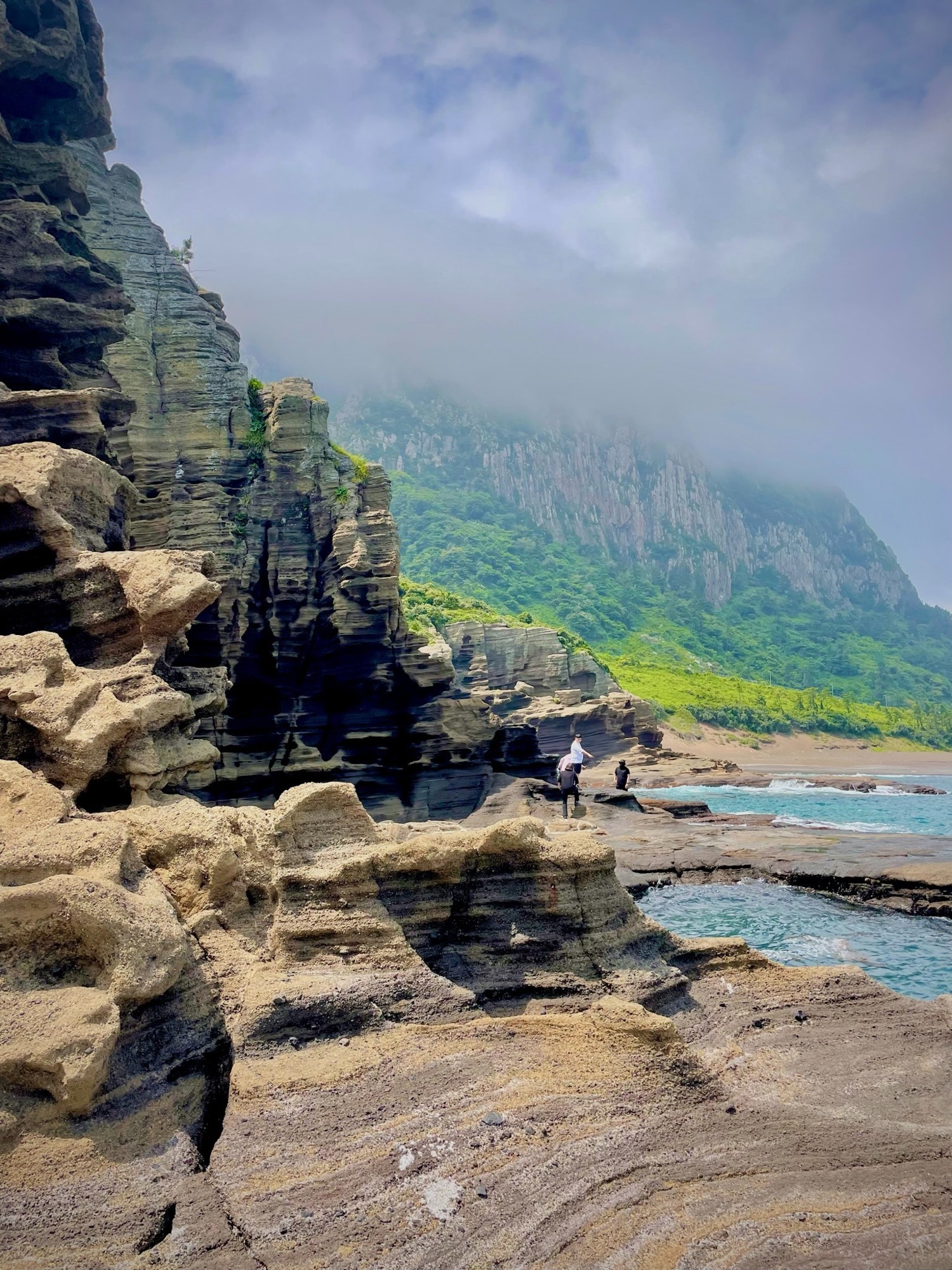 Rocky coastal ledges below misty green mountains